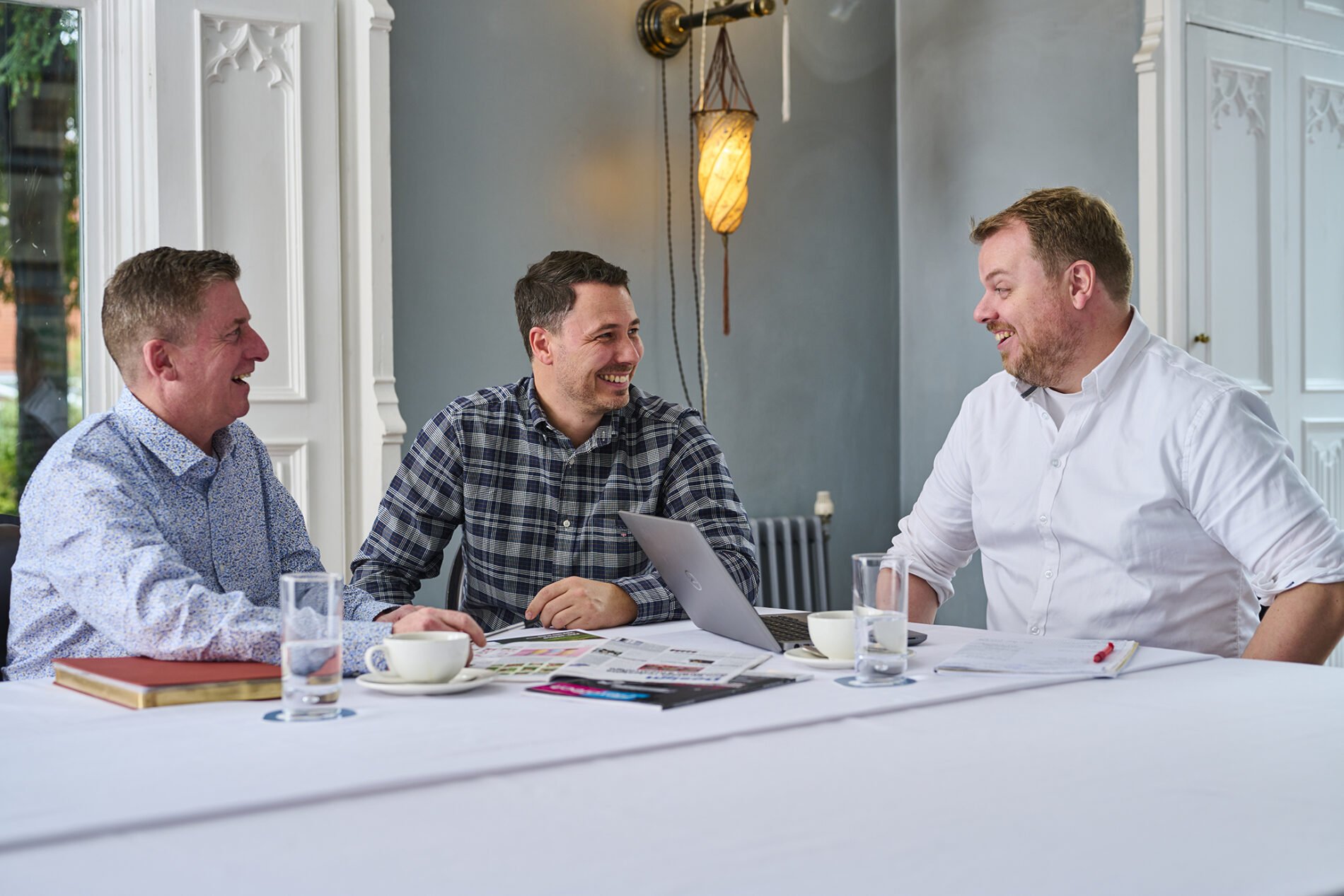 three men chatting at a desk